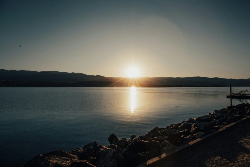 Beautiful serene sunset over a calm lake with mountain silhouettes in the distance